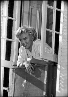 an old photo of a woman leaning out of a window with her hand on the side