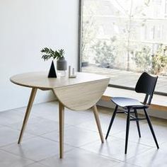 two chairs and a table in front of a window with a plant on the side