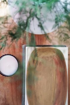 a candle sitting on top of a wooden table next to a box with a painting