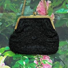 "Vintage lightweight evening purse from the 1970's made in Hong Kong by Richere. Black satin handbag has a floral design in small black glass beads. Gold tone engraved frame and kiss closure with double wrist chain. Interior is black satin with one pocket. Purse measures 7\" by 5\". Clean condition inside and out. Please see photos for more details. All items are vintage that are preowned. All of the items may show some form of wear due to their age. Please kindly remember that these items are a Elegant Black Coin Purse For Evening, Elegant Black Evening Coin Purse, Vintage Evening Bag With Chain Strap, Black Rectangular Evening Coin Purse, Elegant Evening Bags With Black Beads, Black Evening Coin Purse Clutch, Antique Style Evening Clutch Bag, Black Clutch Coin Purse For Evening, Antique Beaded Evening Bag