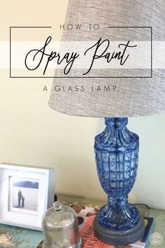 a blue lamp sitting on top of a table next to a glass jar and book