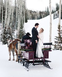 a bride and groom are standing in the snow next to a horse drawn sleigh