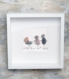 three pebbles holding hands in a white frame