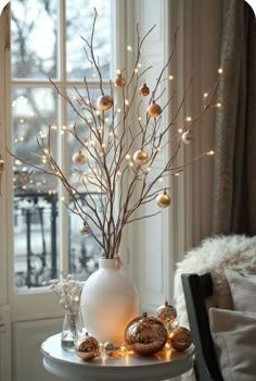 a white vase filled with ornaments on top of a table next to a large window