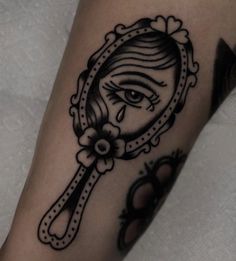 a close up of a person's arm with a tattoo on it and an eye looking in a mirror