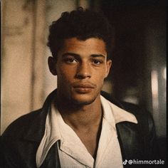 a young man wearing a black leather jacket and white shirt is looking at the camera