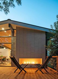 two lounge chairs sitting on top of a wooden deck next to an open fire place