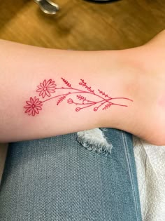 a person with a tattoo on their arm that has flowers and leaves drawn on it