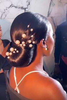 a woman is getting her hair done with pearls