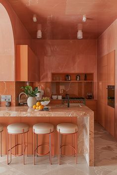 an orange kitchen with marble counter tops and stools