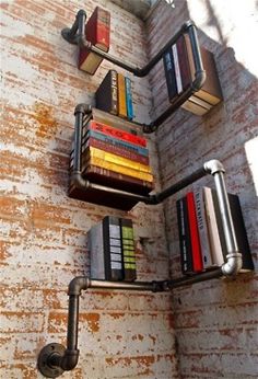 some books are sitting on the wall with metal pipes