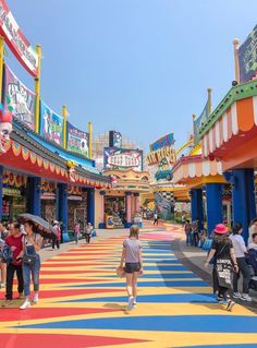 people are walking through an amusement park with brightly colored floors and colorful signs on the walls