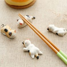 three small cats and two chopsticks on a table