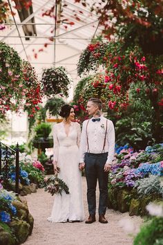 a man and woman standing next to each other in front of flowers