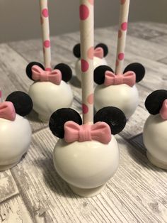 mickey and minnie mouse cake pops with pink bows are on a table next to each other