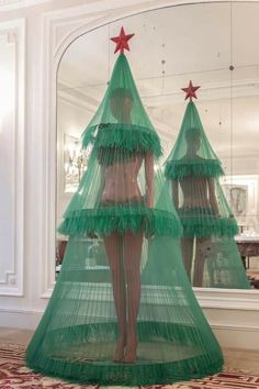 there is a green christmas tree in the middle of a room with two mannequins