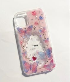 a phone case with pink butterflies and jewels on the back, sitting on a white surface