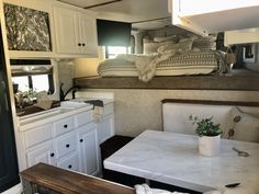 a kitchen and dining area inside an rv with white cabinets, counter tops and drawers