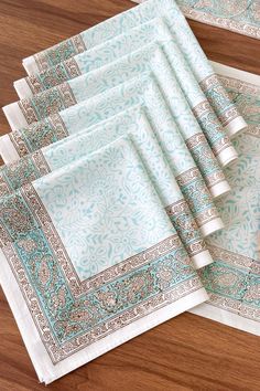 six place mats with blue and white designs on them sitting on a wooden table top