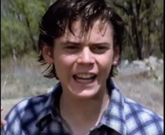 a young man making a face while standing in the woods