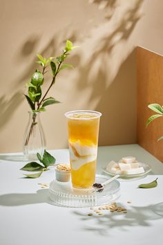 a glass filled with liquid sitting on top of a table next to a flower vase