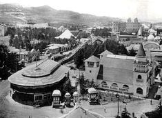 an old black and white photo of a town in the middle of the day with mountains in the background