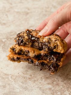 a hand is holding a chocolate chip cookie