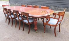 a large wooden table with six chairs around it on the ground next to a building