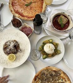 a table topped with lots of different types of food and drinks on top of white plates