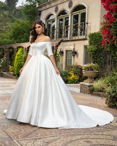 a woman in a white wedding dress standing on a patio with her hands on her hips