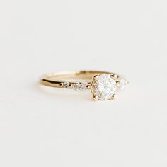 a gold engagement ring with two diamonds on the side and a single diamond in the middle