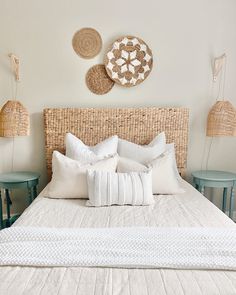 a bed with white linens and wicker headboard next to two side tables