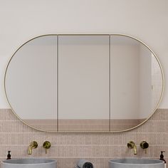 a bathroom with two sinks and a large round mirror above it's countertop