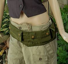 a mannequin wearing a black vest and khaki pants with an army green belt