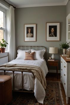 a bed sitting in a bedroom next to two pictures on the wall and a dresser