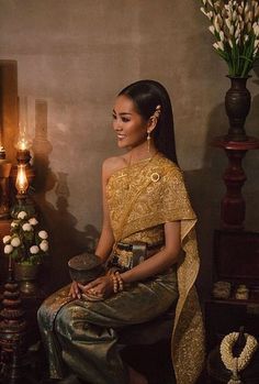 a woman sitting on top of a chair next to a vase filled with flowers