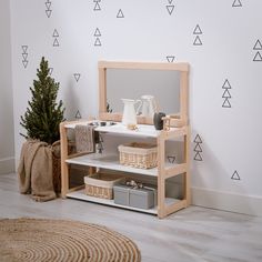 a wooden shelf with baskets and items on it in front of a wall decorated with triangles