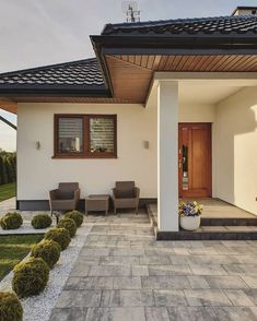 the front entrance of a modern home with stone walkways and potted plants on either side