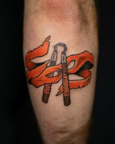 an orange and black flag with two crossed wrenches on the leg, which is also part of a tattoo