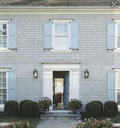 a house with white shutters and blue doors