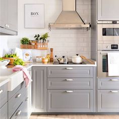 a kitchen with gray cabinets and white counter tops is pictured in this image, there are pots on the stove