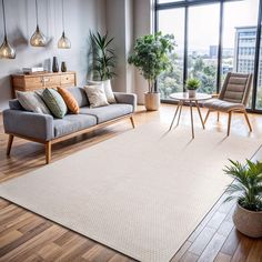 a living room filled with lots of furniture and plants on top of a hard wood floor