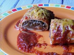 an orange plate topped with meat and cheese covered enchilada rolls on top of sauce