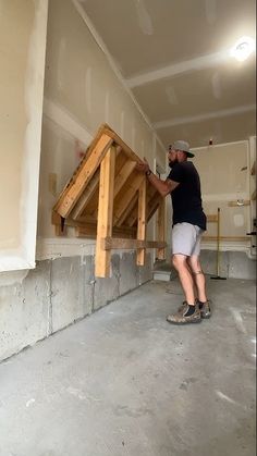 a man is working on some wood in a room with unfinished walls and flooring