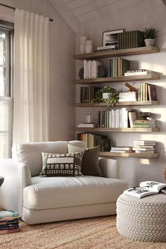 a living room filled with furniture and bookshelves next to a window covered in white curtains