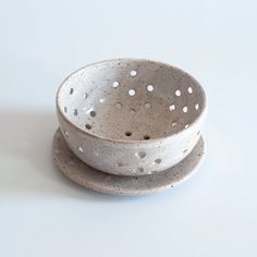 two ceramic bowls sitting side by side on top of each other with holes in them