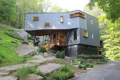 a modern house in the woods with stairs leading up to it's second story