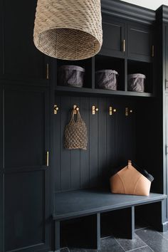 a room with black cabinets and baskets hanging from the hooks on the wall above it