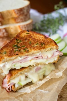 a sandwich cut in half sitting on top of a piece of paper next to sliced apples