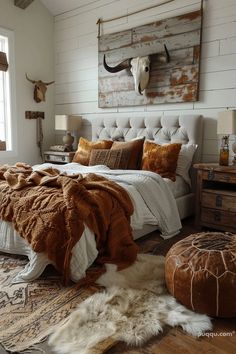 a bedroom with a large bed and cow head on the wall above it, along with two stools